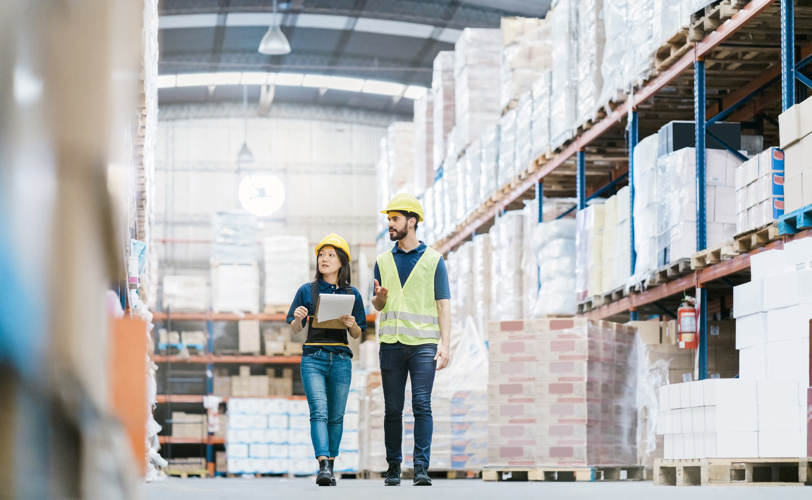 Two people in PPE walking through warehouse